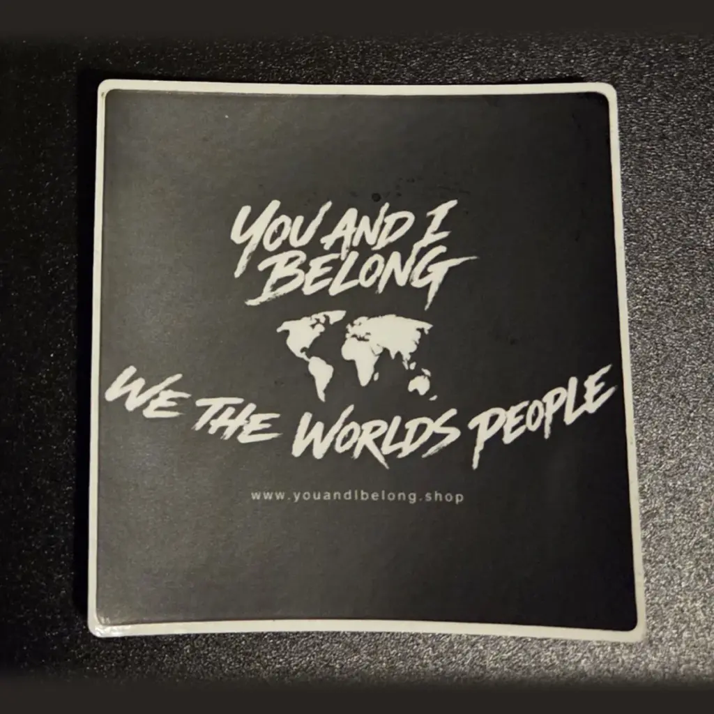 Classic black You and I Belong sticker with a white world map and the words We The Worlds People