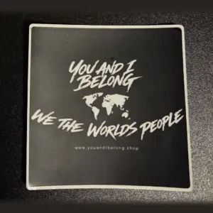 Classic black You and I Belong sticker with a white world map and the words We The Worlds People