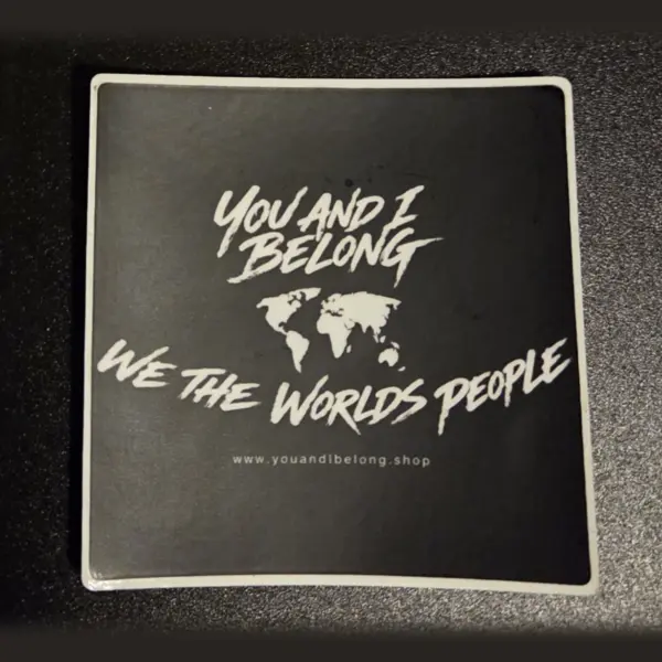 Classic black You and I Belong sticker with a white world map and the words We The Worlds People